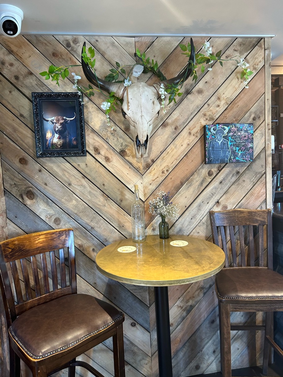 chairs and table in front of wood wall with skull on wall