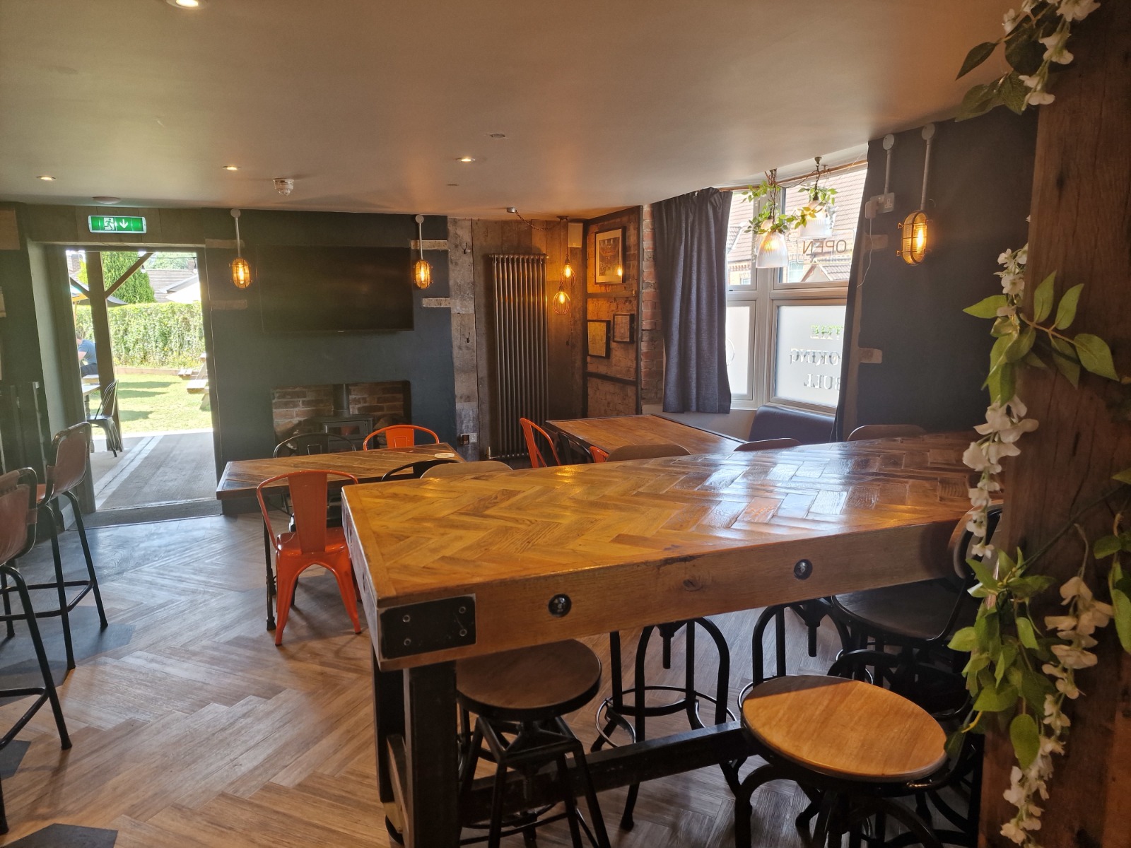 tables and chairs on wooden floor with large window and open door leading to garden