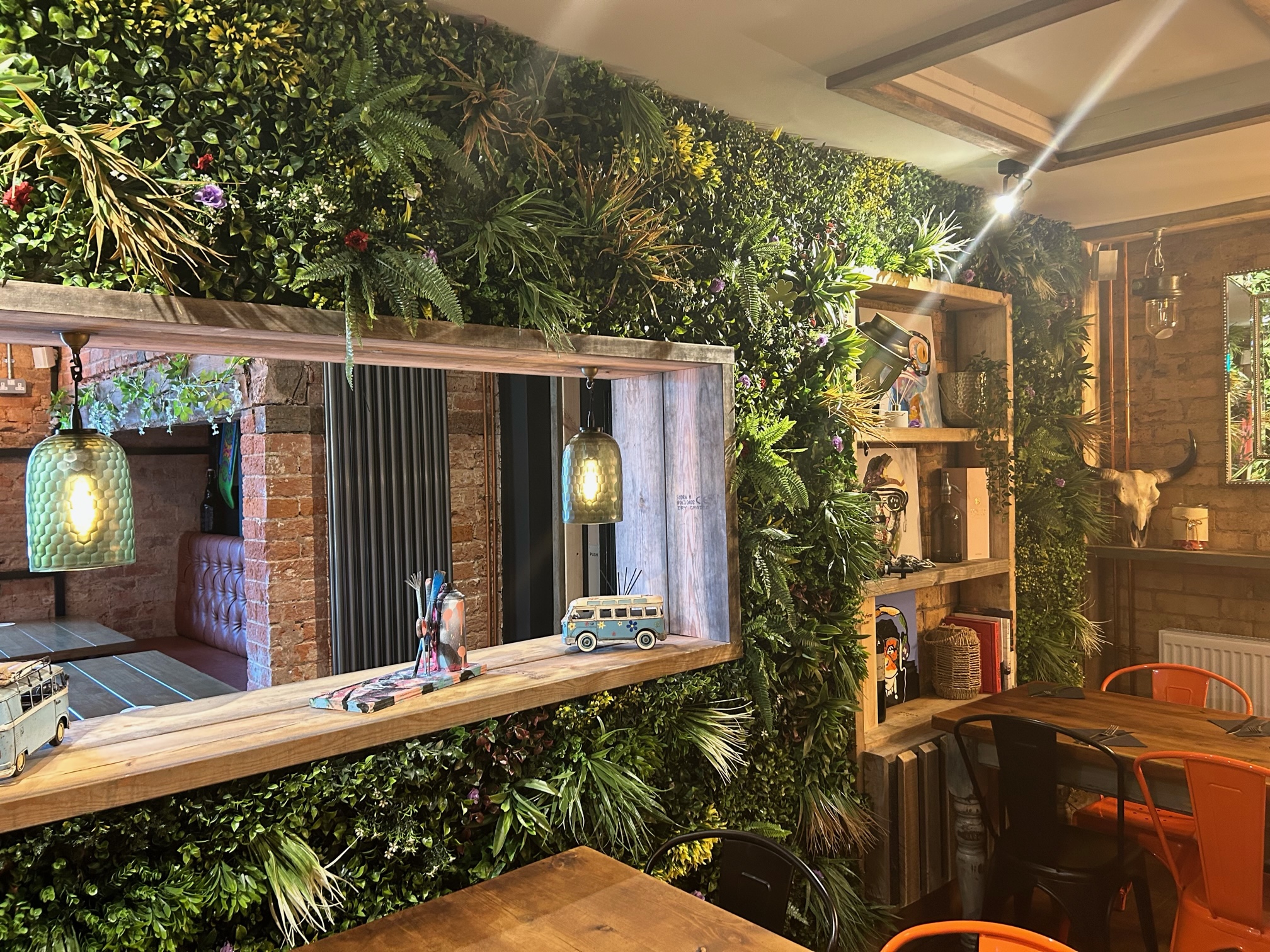 wall with shelves covered with greenery with hatch in middle 